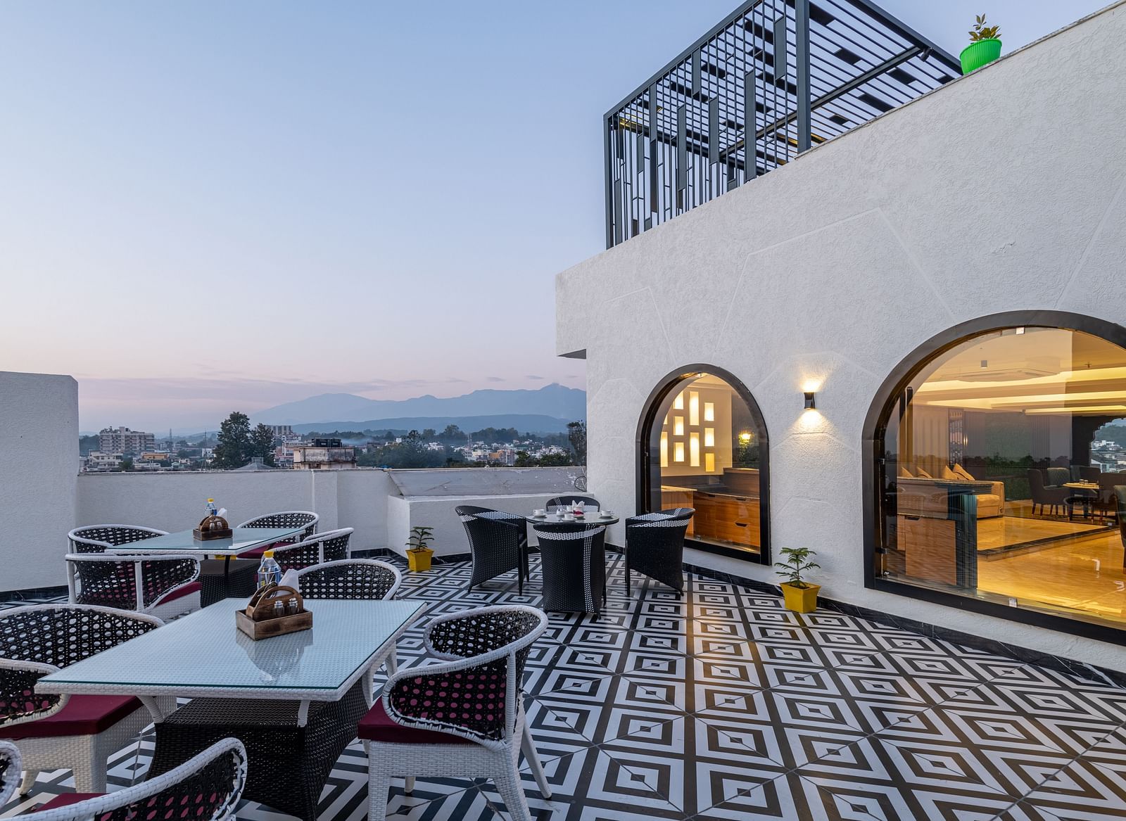 Image of rooftop restaurant Ruttba at DLS Grand Luxotica, Dehradun featuring dining setting on a well furnished floor with the scenic view of Dehradun city