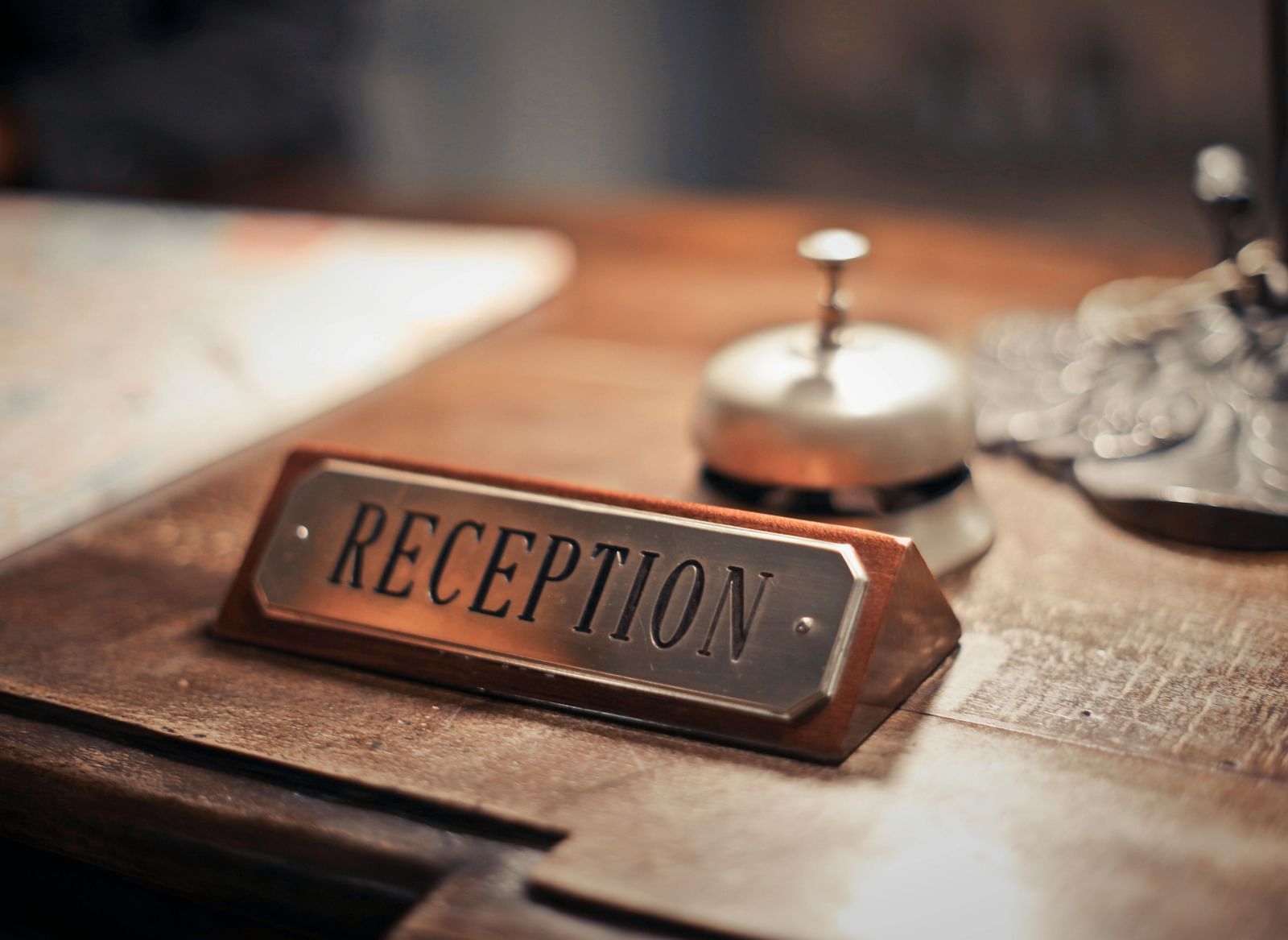 A front desk at a hotel with a reception board and a concierge bell placed on it