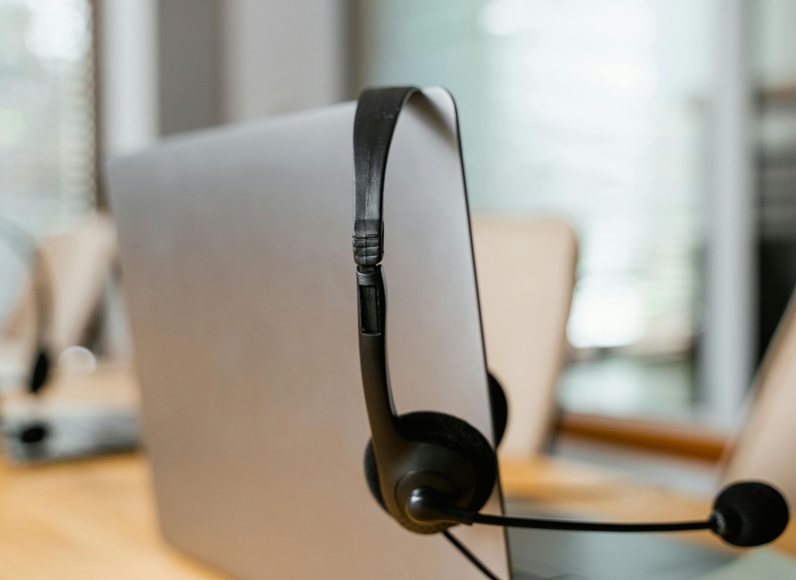 A headphone with a mic hung off a silver laptop screen.