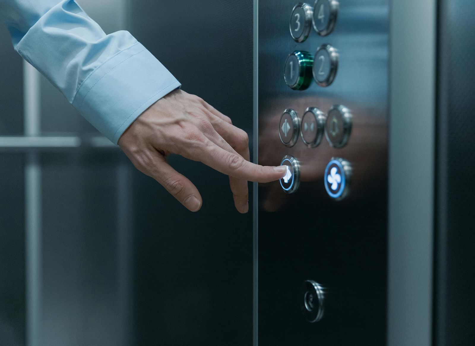 A close up shot of the hand of a man pressing an elevator button