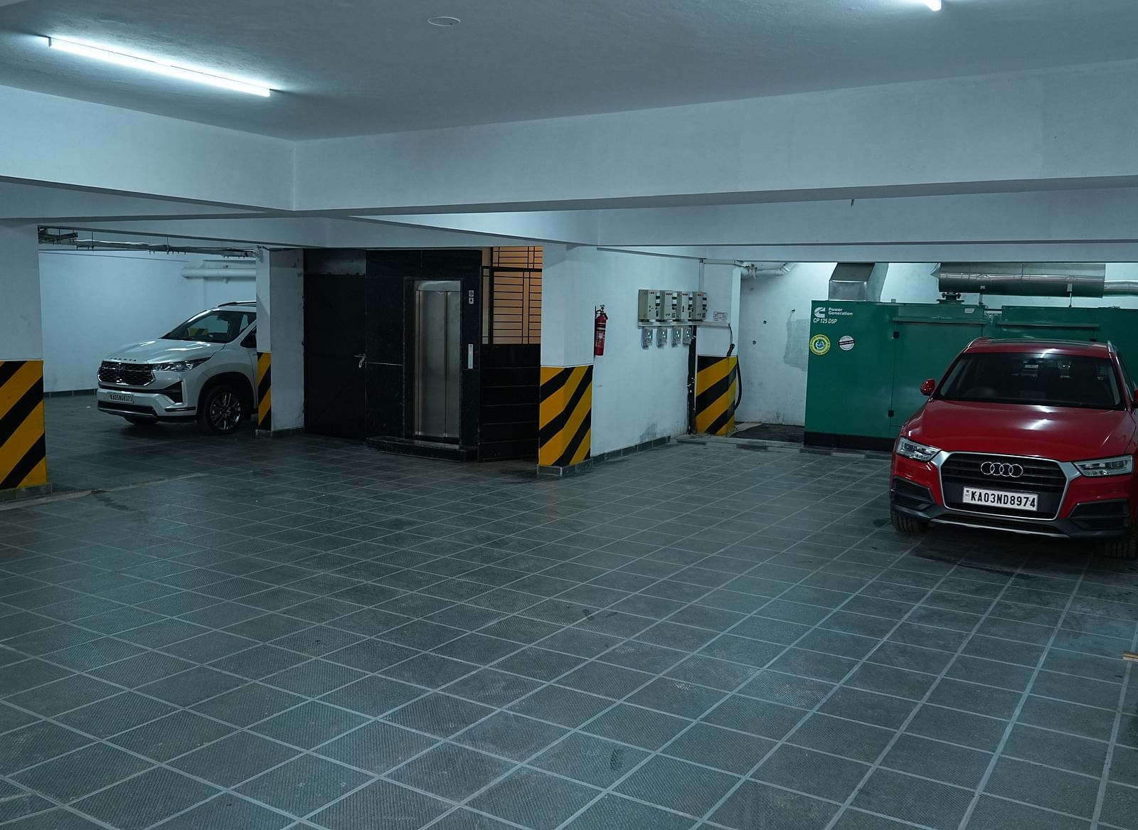a dimly lit parking area with ample space along with SUV cars parked - Hotel Grand Sigma