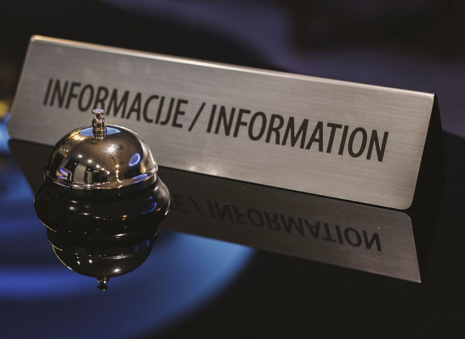 Hotel reception desk with a service bell and an information sign.