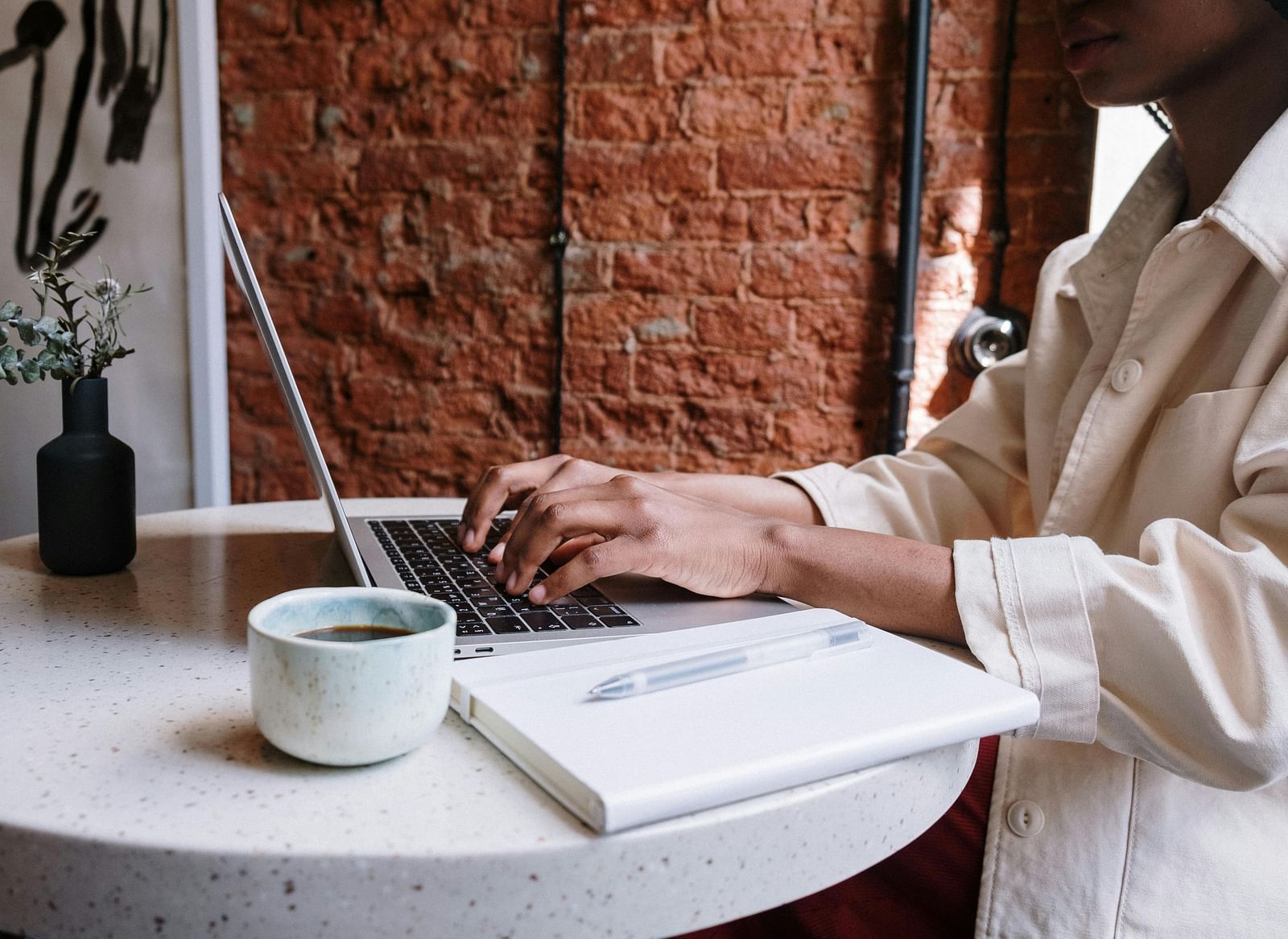 A woman working at a table with laptop, coffee mug and decorg