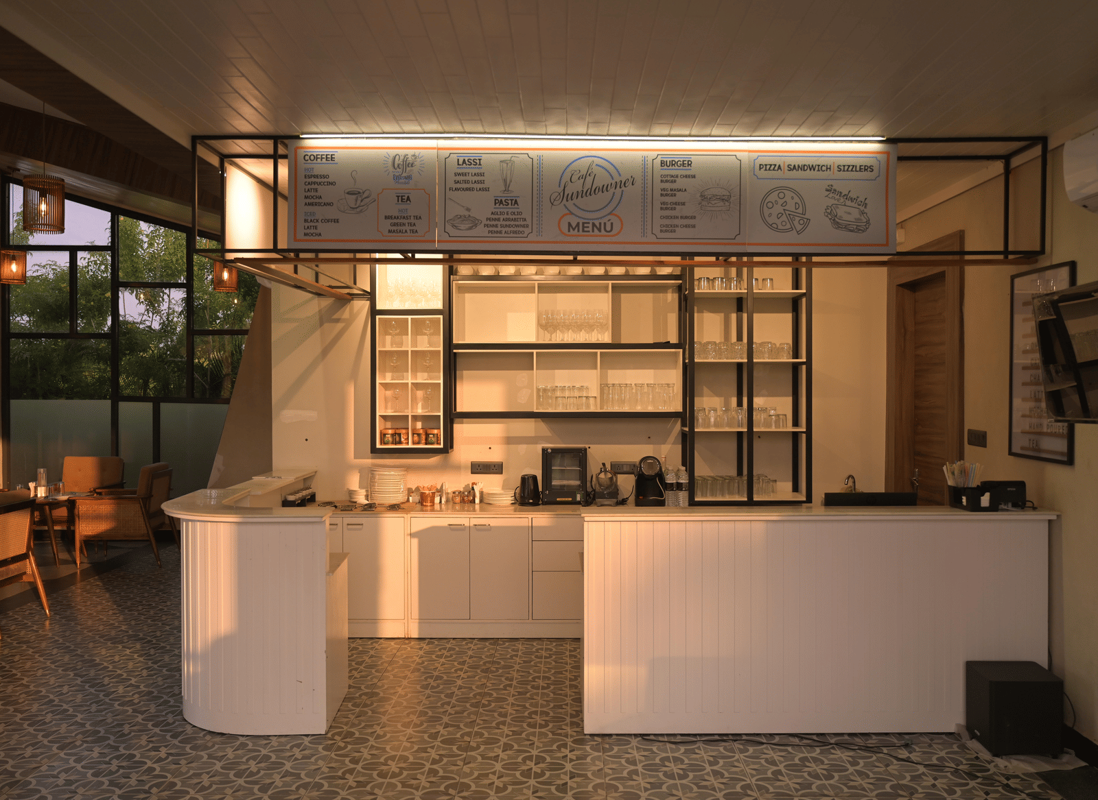 A modern cafe counter with clean lines, open shelving, and warm ambient lighting at Hotel Sonar Bangla Mayapur.