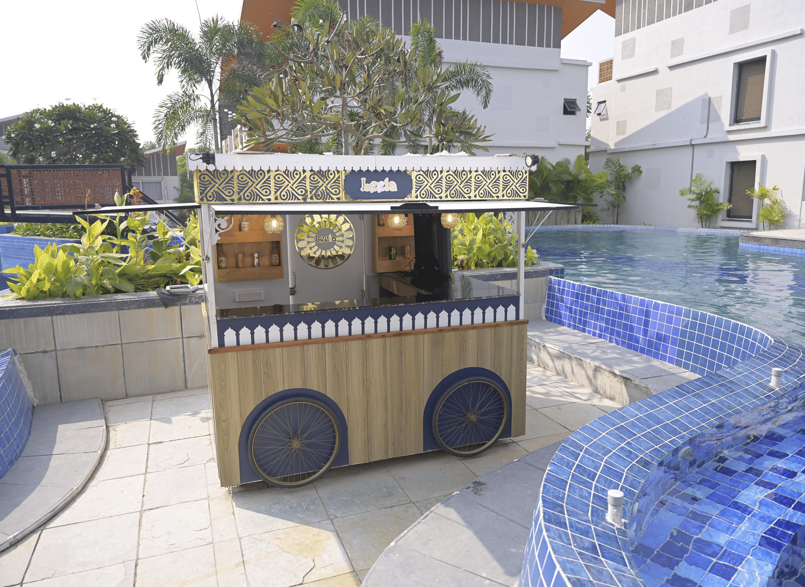 A charming poolside refreshment cart set beside the blue-tiled pool area at Hotel Sonar Bangla Mayapur.