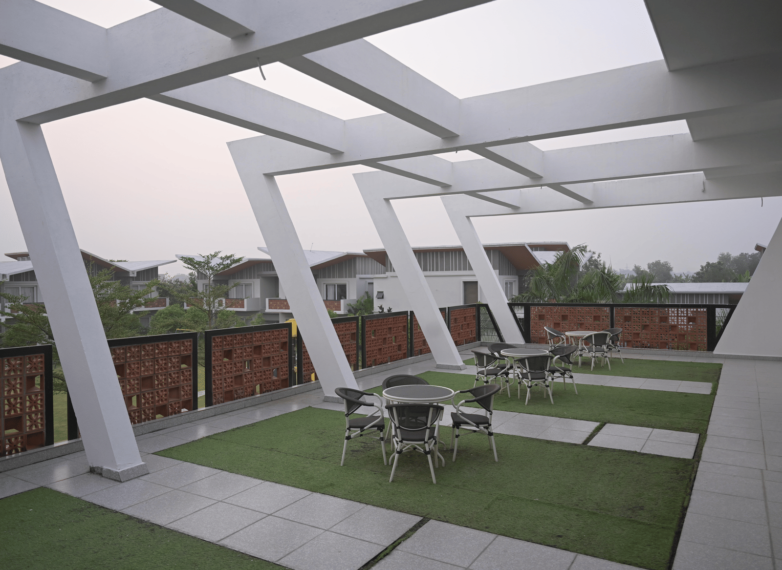 Rooftop seating with modern architectural beams and garden-style flooring at Hotel Sonar Bangla Mayapur.