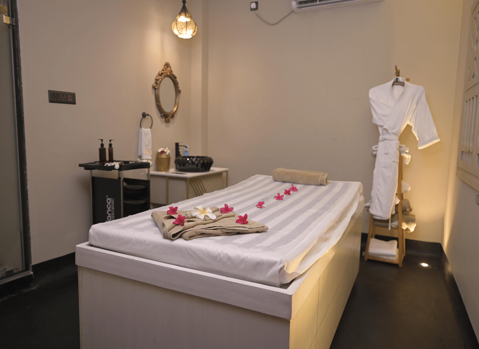 A spa room with a neatly arranged massage bed and treatment essentials at Hotel Sonar Bangla Mayapur.