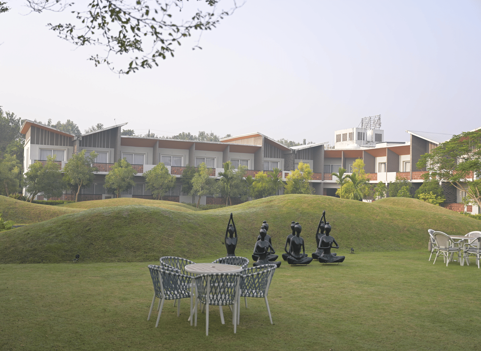 Scenic lawn area with outdoor tables set against a backdrop of villas and landscaped gardens at Hotel Sonar Bangla Mayapur.