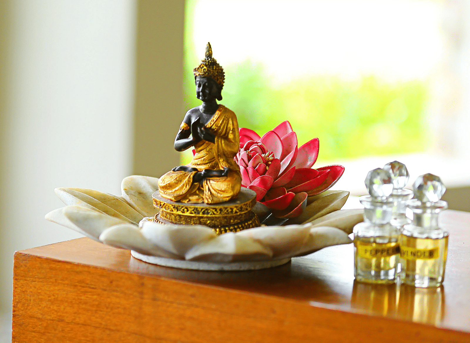 A small statue of Lord Buddha with two vials of essential oil kept besides it - Ivory Destinations