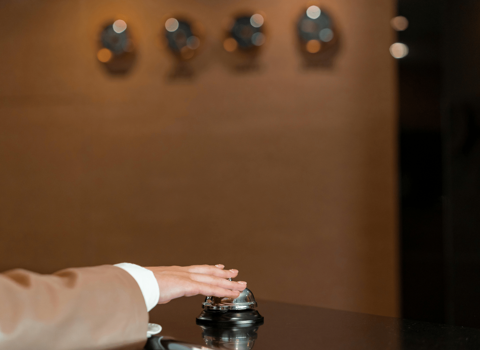 A person's hand ringing a bell placed on a counter.