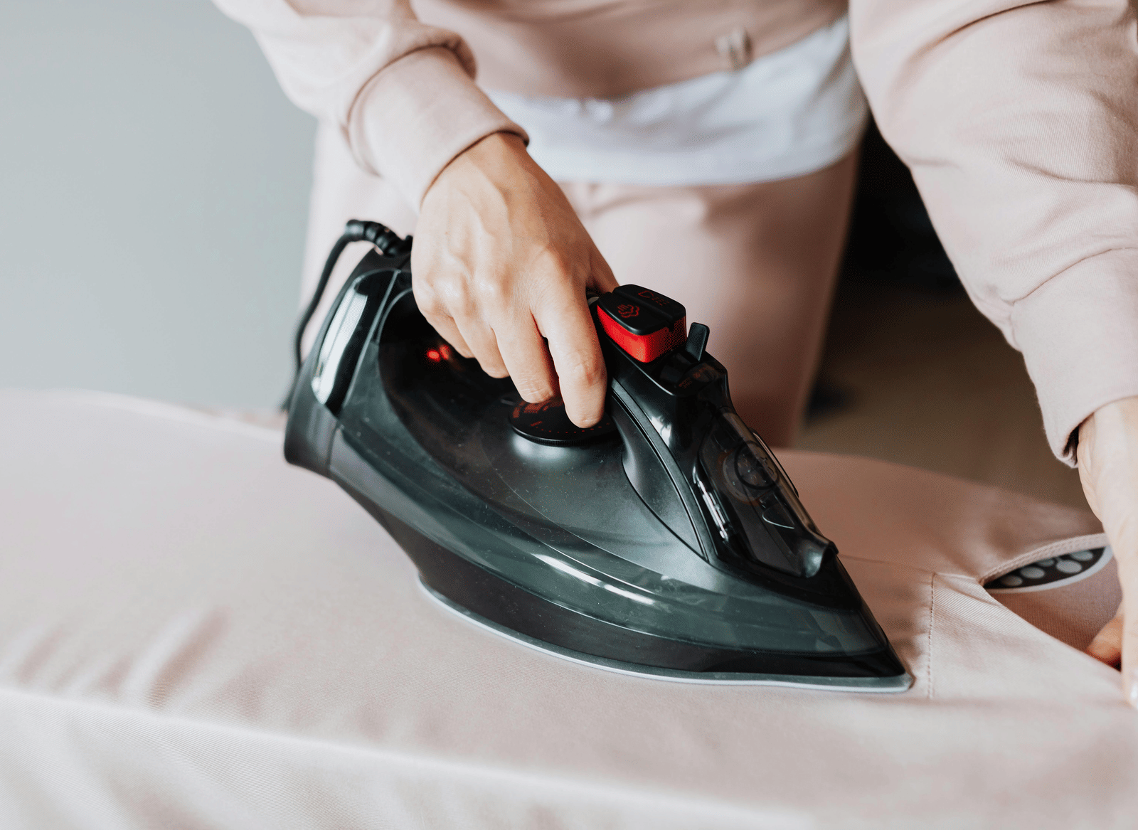 A person wearing a uniform ironing a piece of cloth placed on a table.