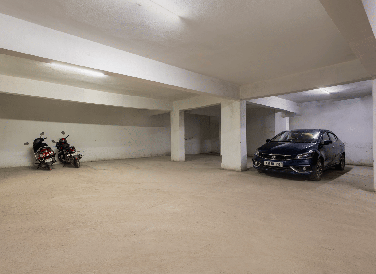 Indoor parking of Kove Smart Stays seen with few parked vehicles, ample space, and overhead lighting.