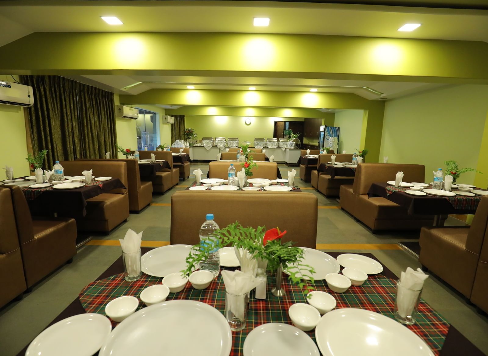 Close-up of tables set with plates and bottles on a carpeted floor at Krushnai Resort.