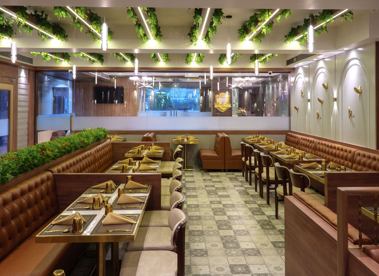 A spacious restaurant with numerous wooden tables and chairs, featuring bright overhead lighting and some greenery - Melior Inn