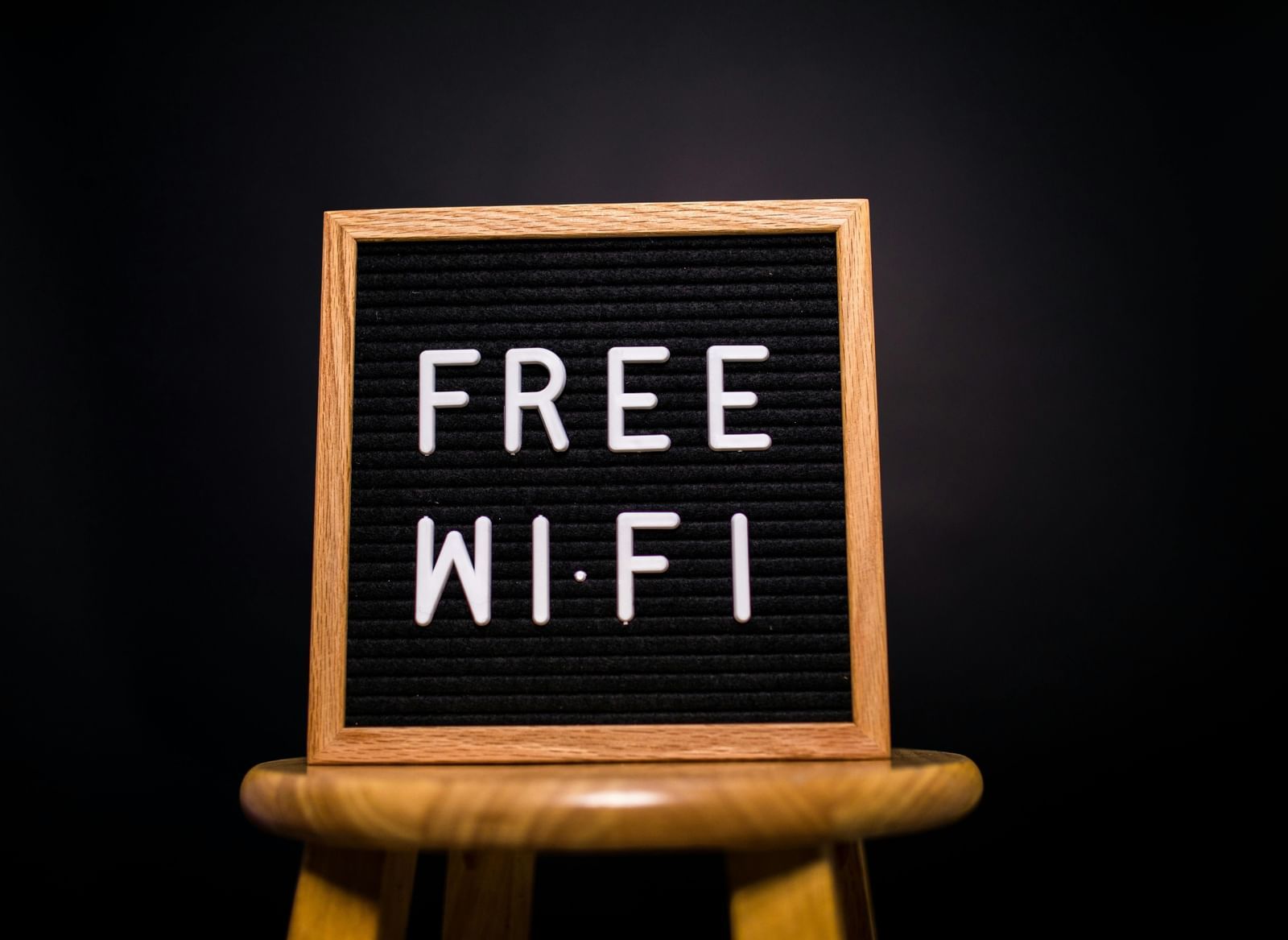 A close-up shot of a small black letterboard sign on a wooden stool. 
