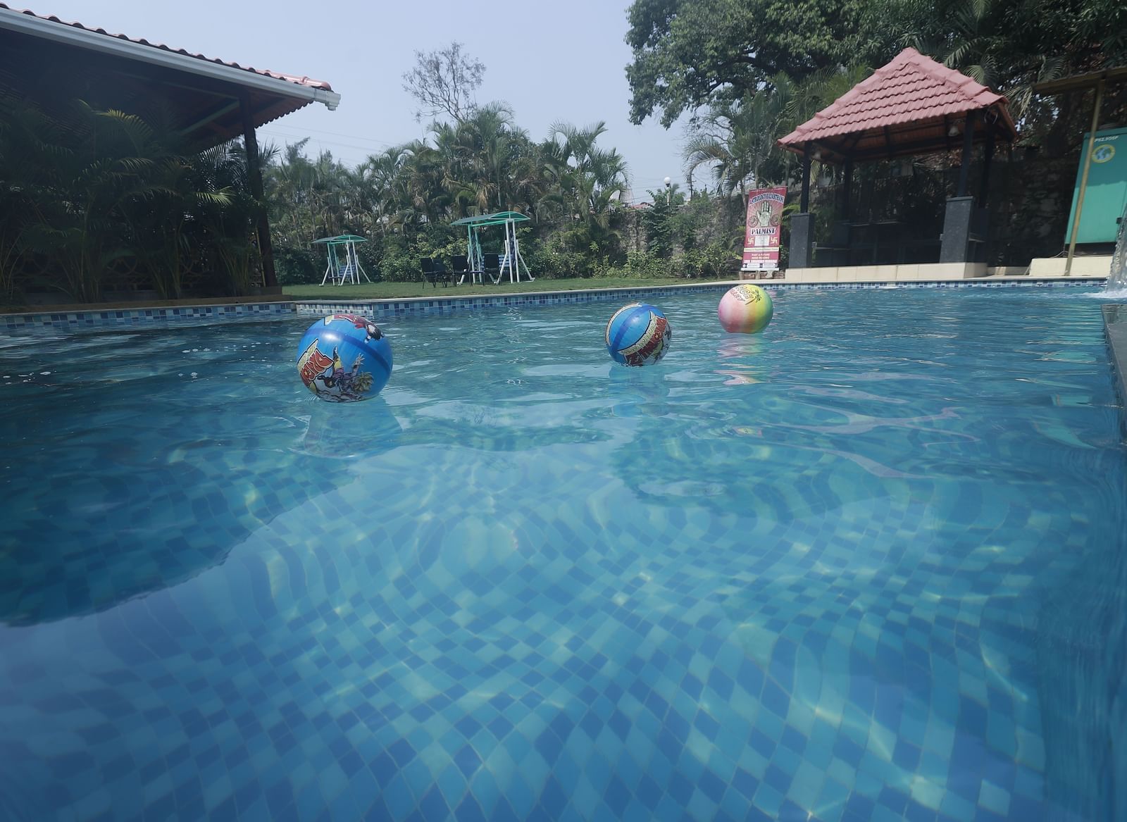 Poolside view with floating colourful beach balls, trees, and a gazebo at Mountview Resort.