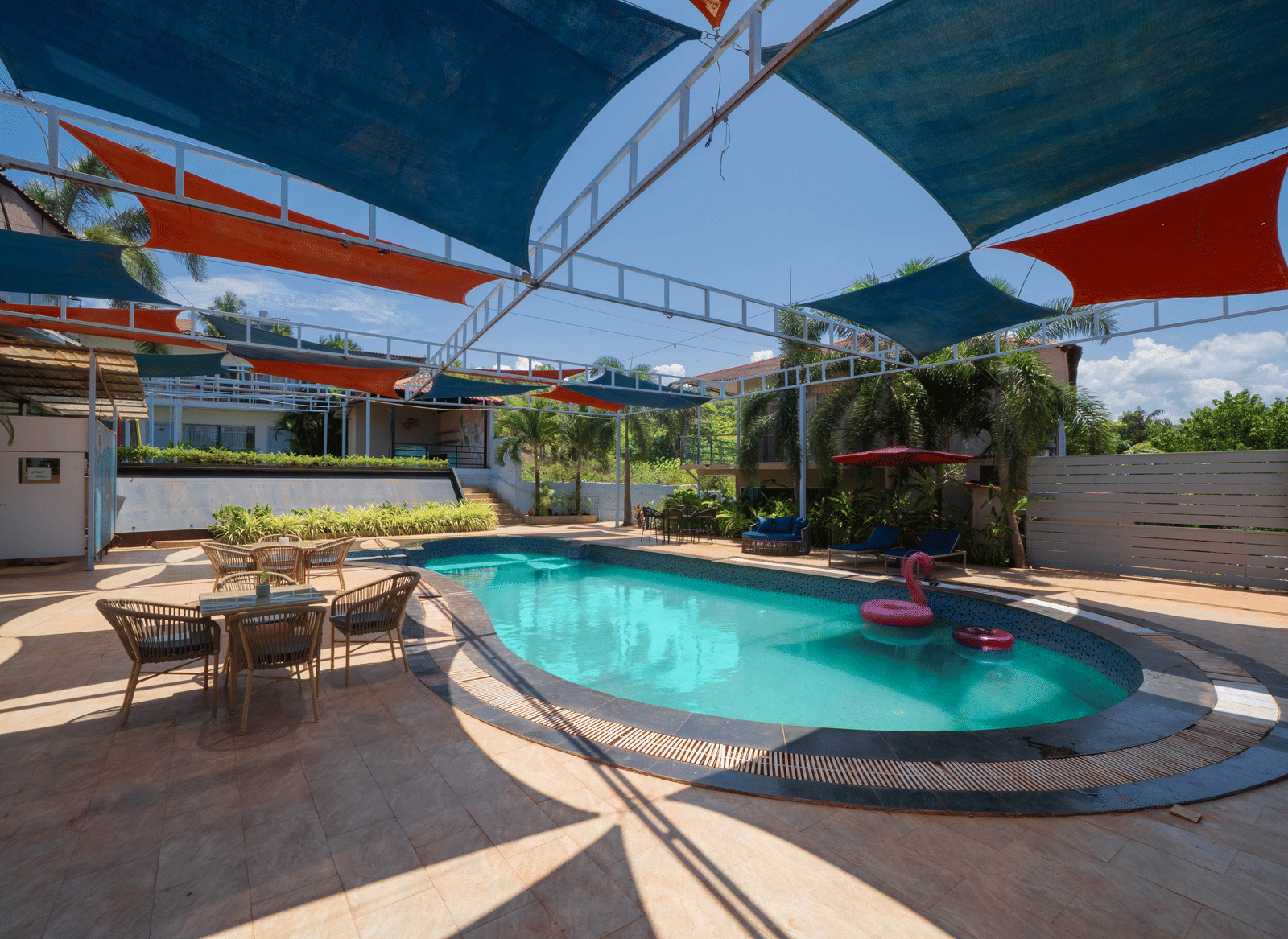 An oval-shaped swimming pool featuring a seating area beside it and shaded spots for relaxation - Perfectstayz Koko Maya