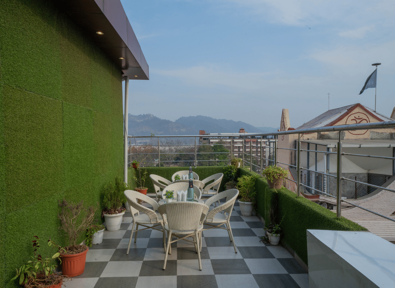 Rooftop terrace seating area with tables and chairs and a view of the surrounding hills - Perfectstayz Premium at Har Ki Pauri Road (Ganga Heights)