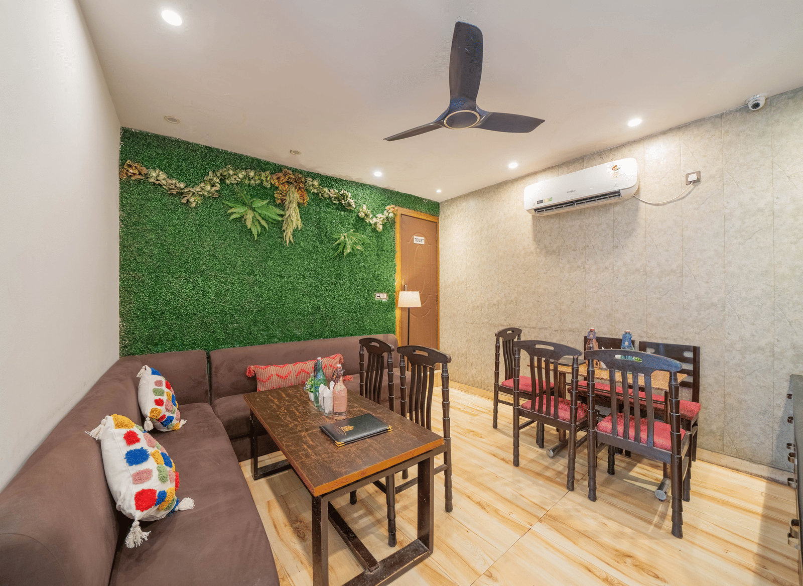 Lounge or dining area inside with a ceiling fan, tables, and chairs, featuring a green wall accent - Perfectstayz Premium at Har Ki Pauri Road (Ganga Heights)