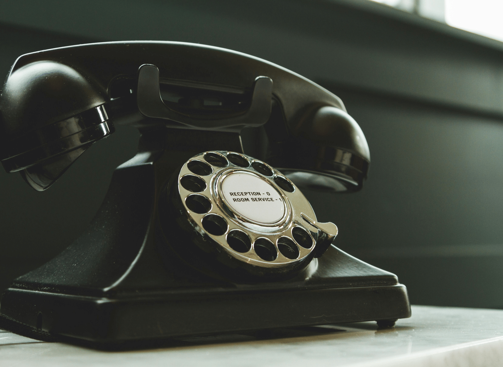 A vintage rotary dial telephone placed on a table.