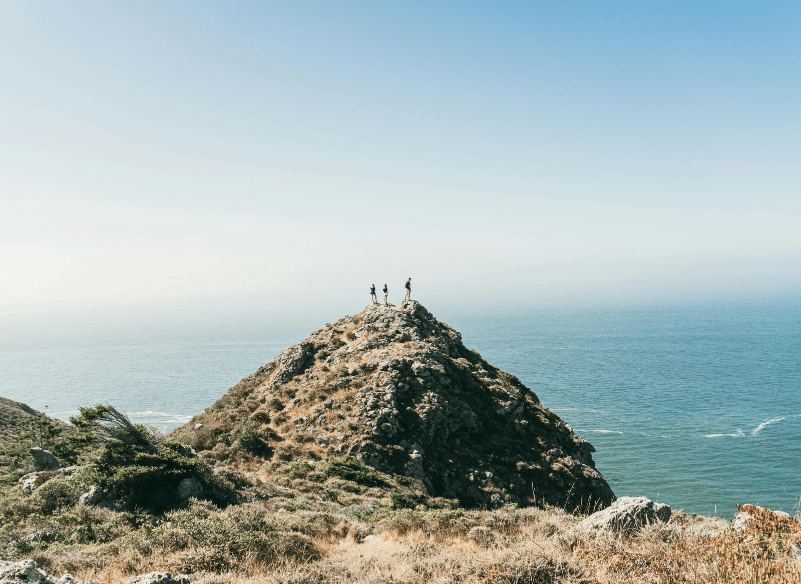 People standing on a cliff edge overlooking the sea.