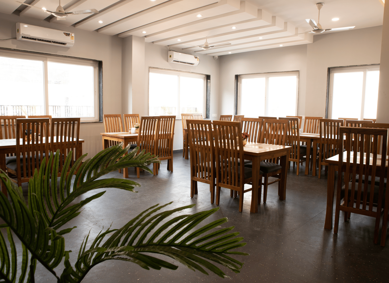 A dining area with tables, chairs, and a potted plant at Perfectstayz Premium Laxmi Heritage.