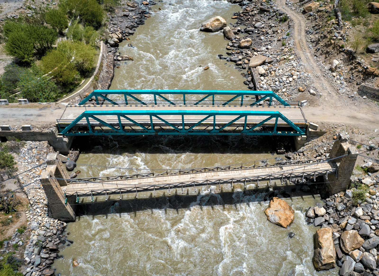 Aerial view of 2 bridges connecting 2 rocky lands, with water flowing beneath.