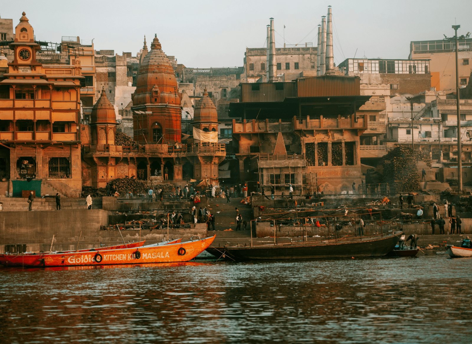 Boats rest along the river beside the stone steps, with buildings stretching along the banks.
