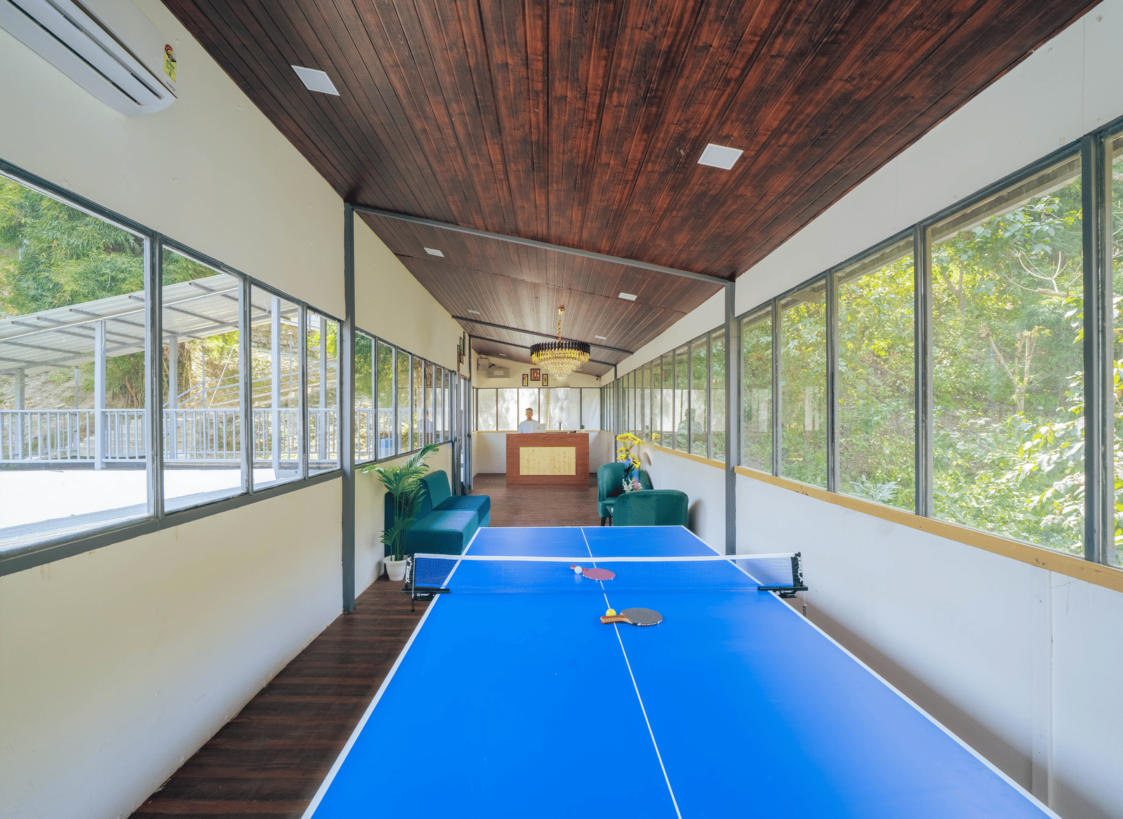 An indoor games area at Perfect Stayz The Jungle Resort contains a table tennis table and large windows.