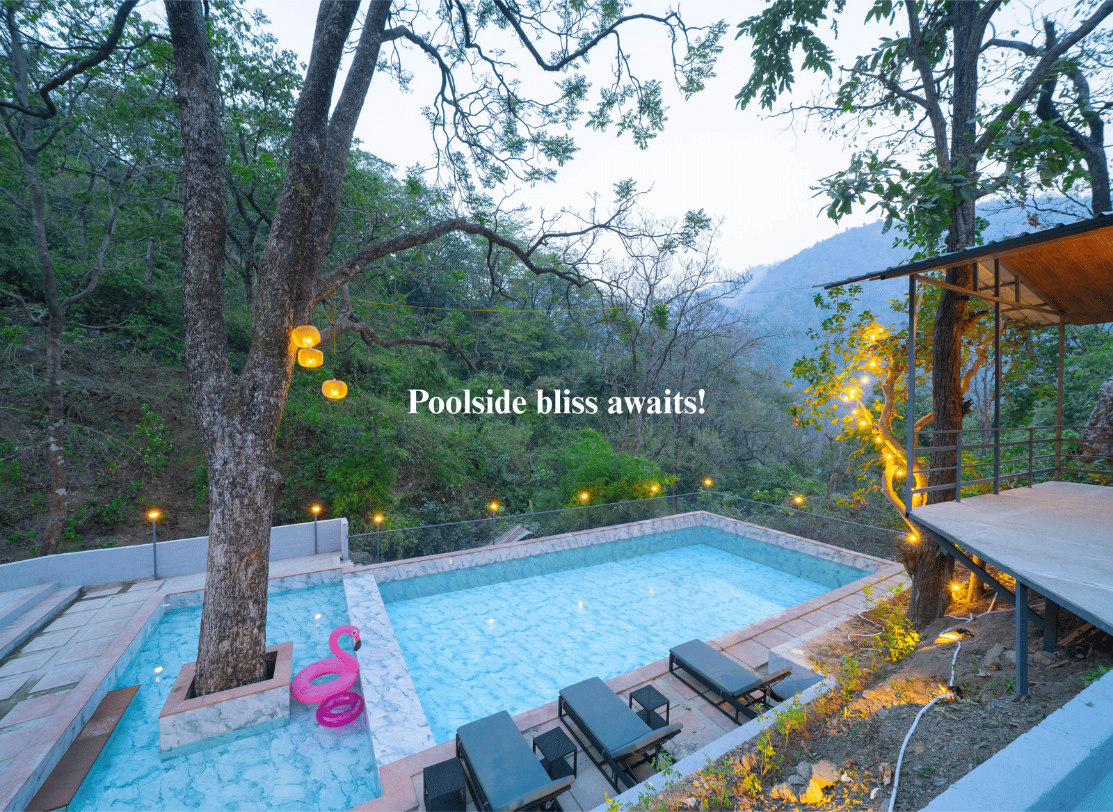 A swimming pool at Perfect Stayz The Jungle Resort is surrounded by trees and lounge chairs.