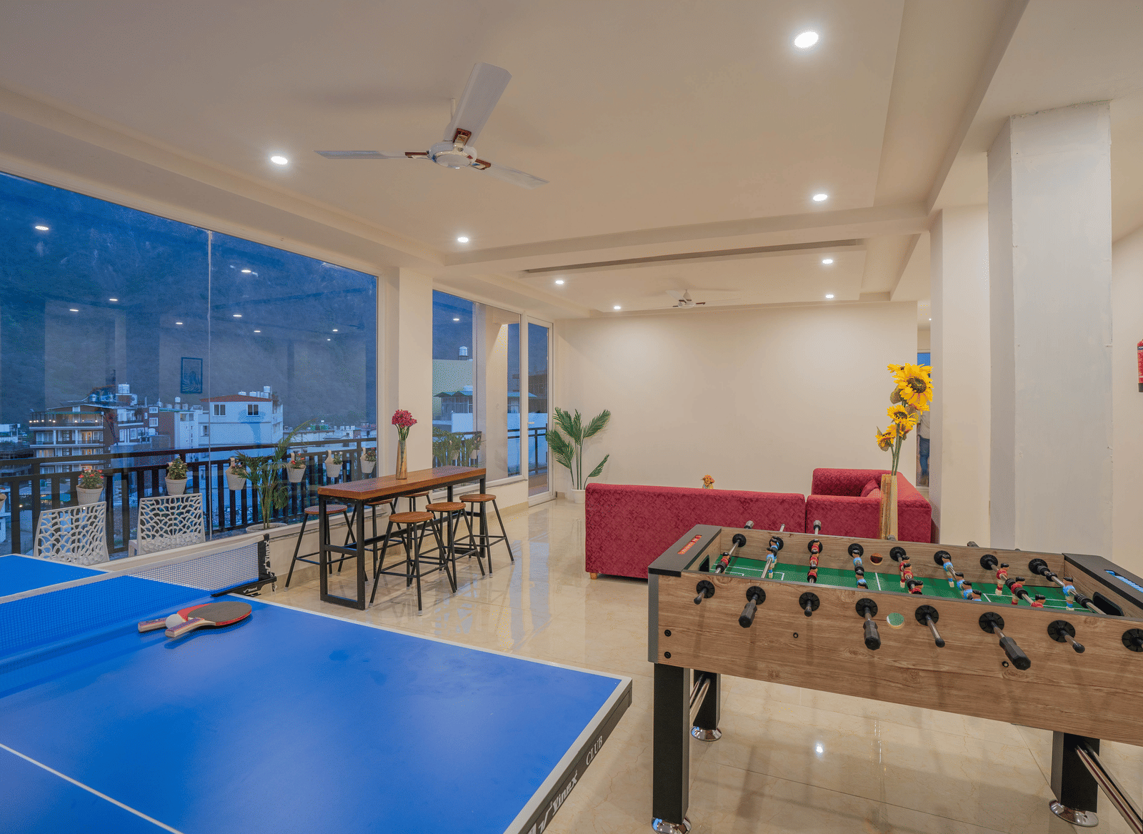 An indoor games room at Perfectstayz Value Alpine Retreat, Rishikesh featuring table tennis board, foosball, and seating area.