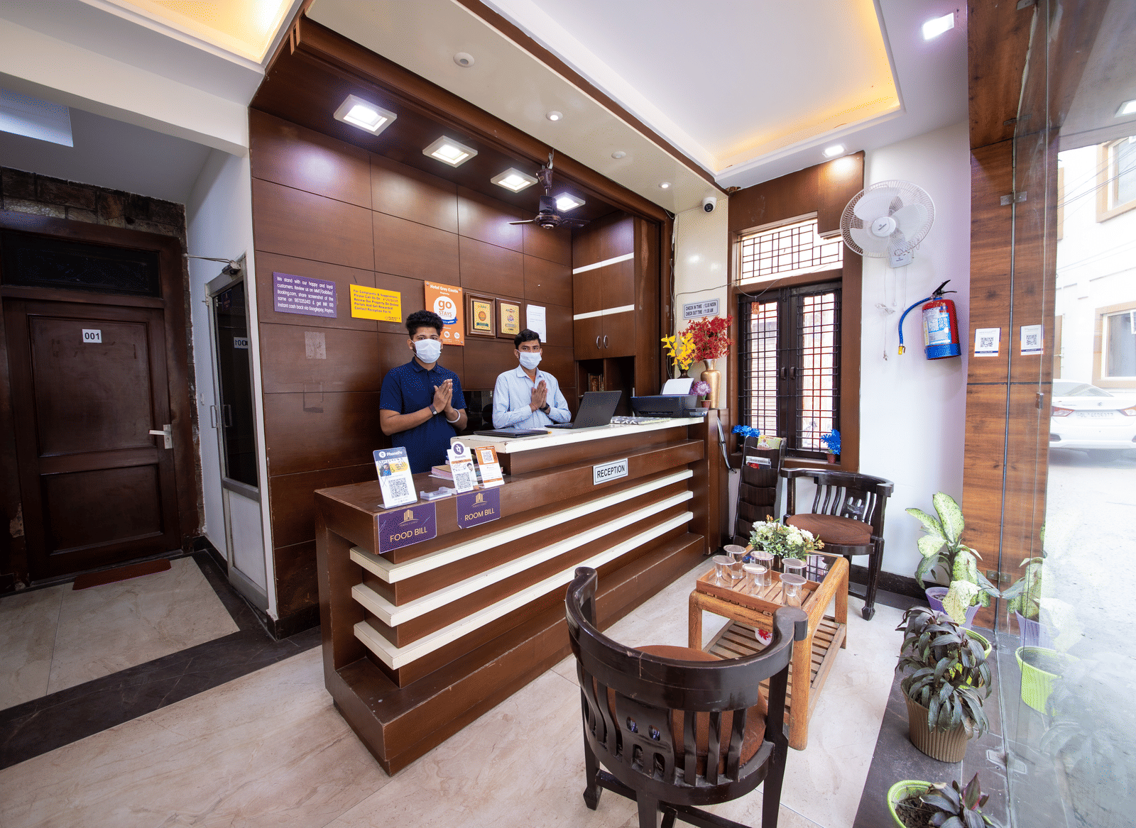 Hotel reception area featuring a modern wooden desk, staff behind the counter, and a small seating area - Perfectstayz Value Grey Castle, Haridwar
