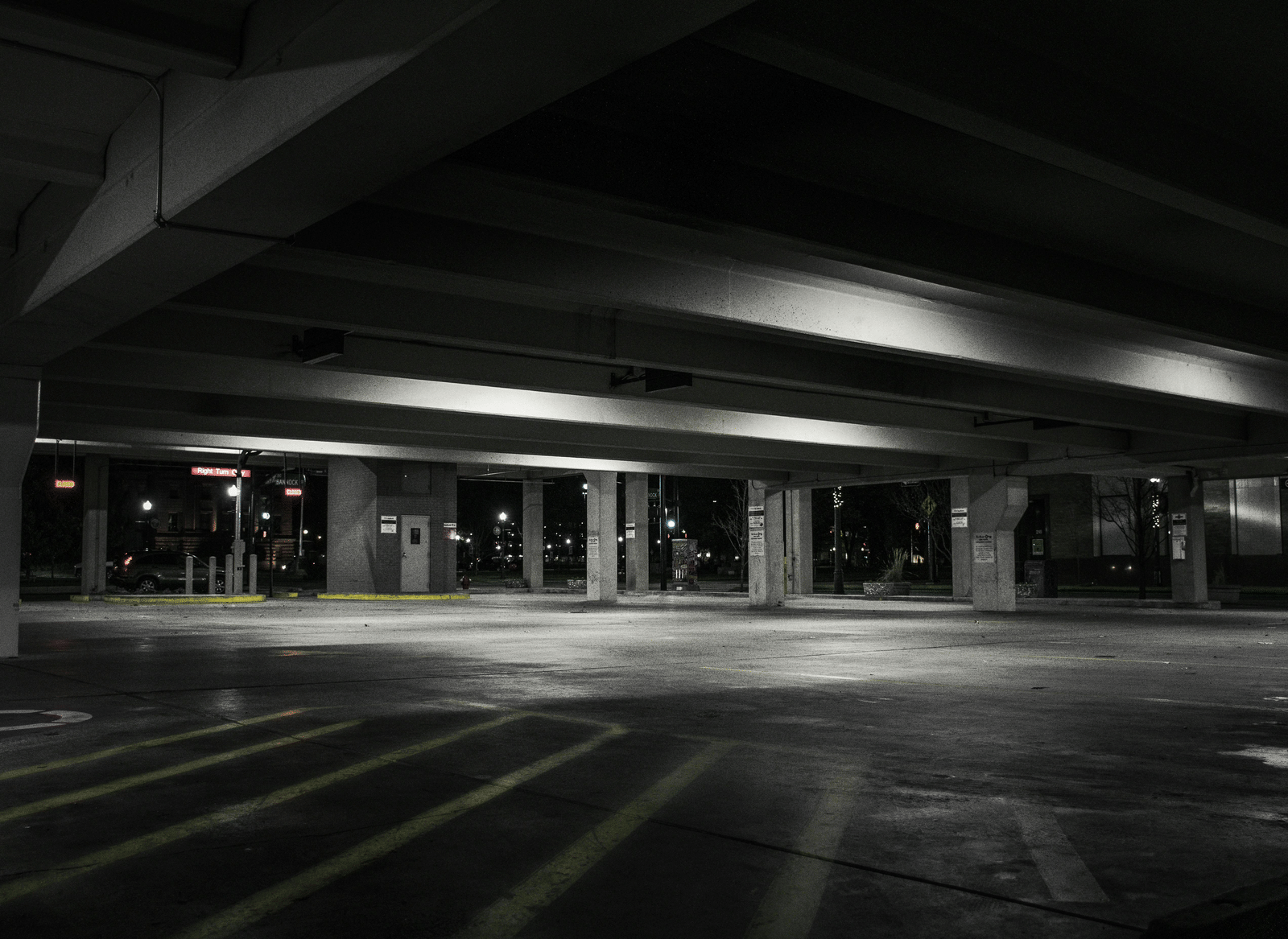 An empty, dimly lit parking garage with parking lines on the concrete floor.