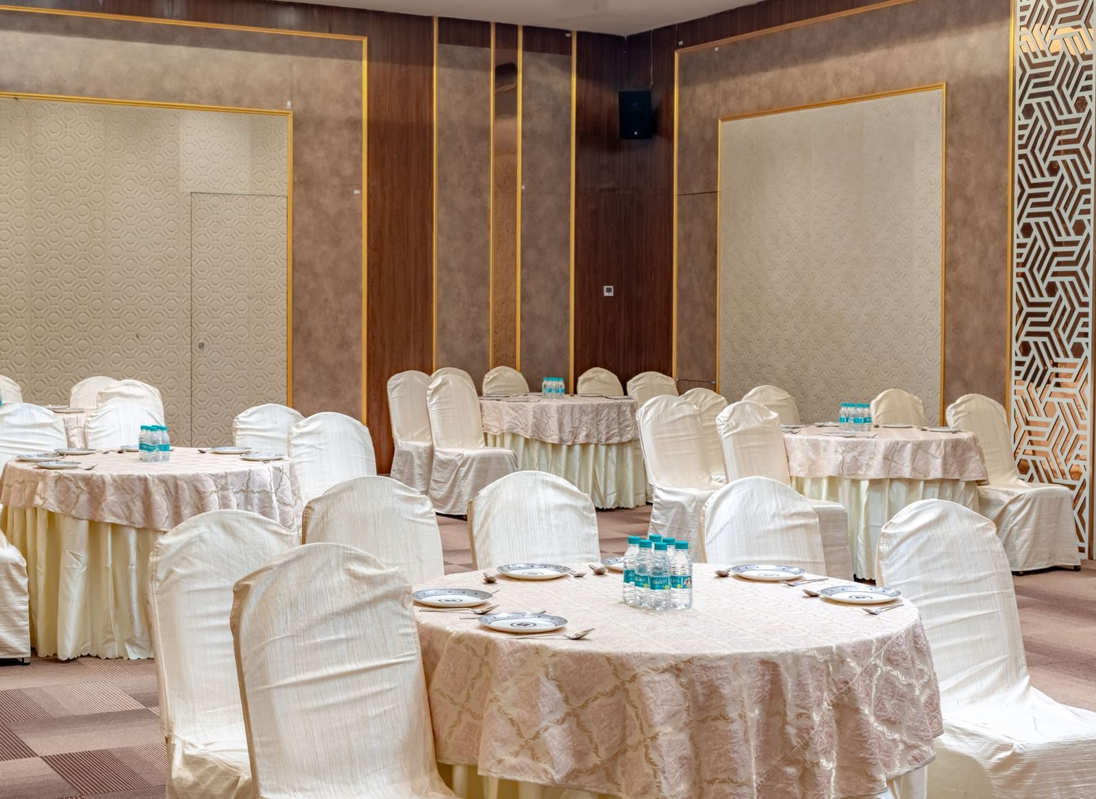 A banquet hall with round tables and elegant chairs | Meetings & Events | Pravasa Hotel, Vijayapura