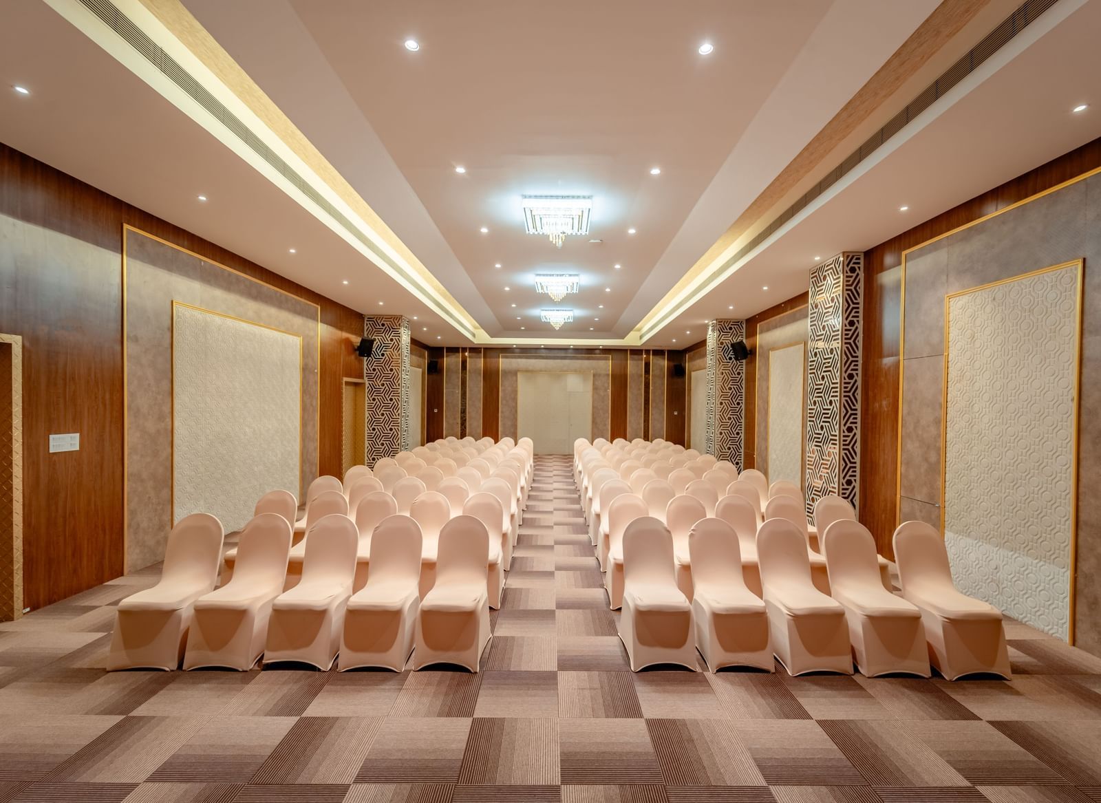 A ballroom set up with rows of beige chairs for a presentation or conference | Meetings & Events | Pravasa Hotel, Vijayapura