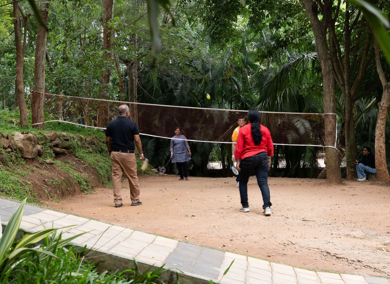 People playing badminton in an outdoor court area | RD's Nature Retreat, Bangalore