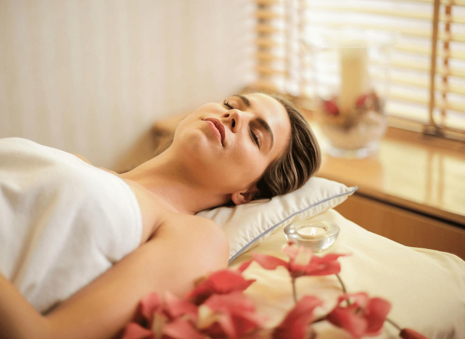 A woman lying down on a bed all relaxed in a brightly lit room.