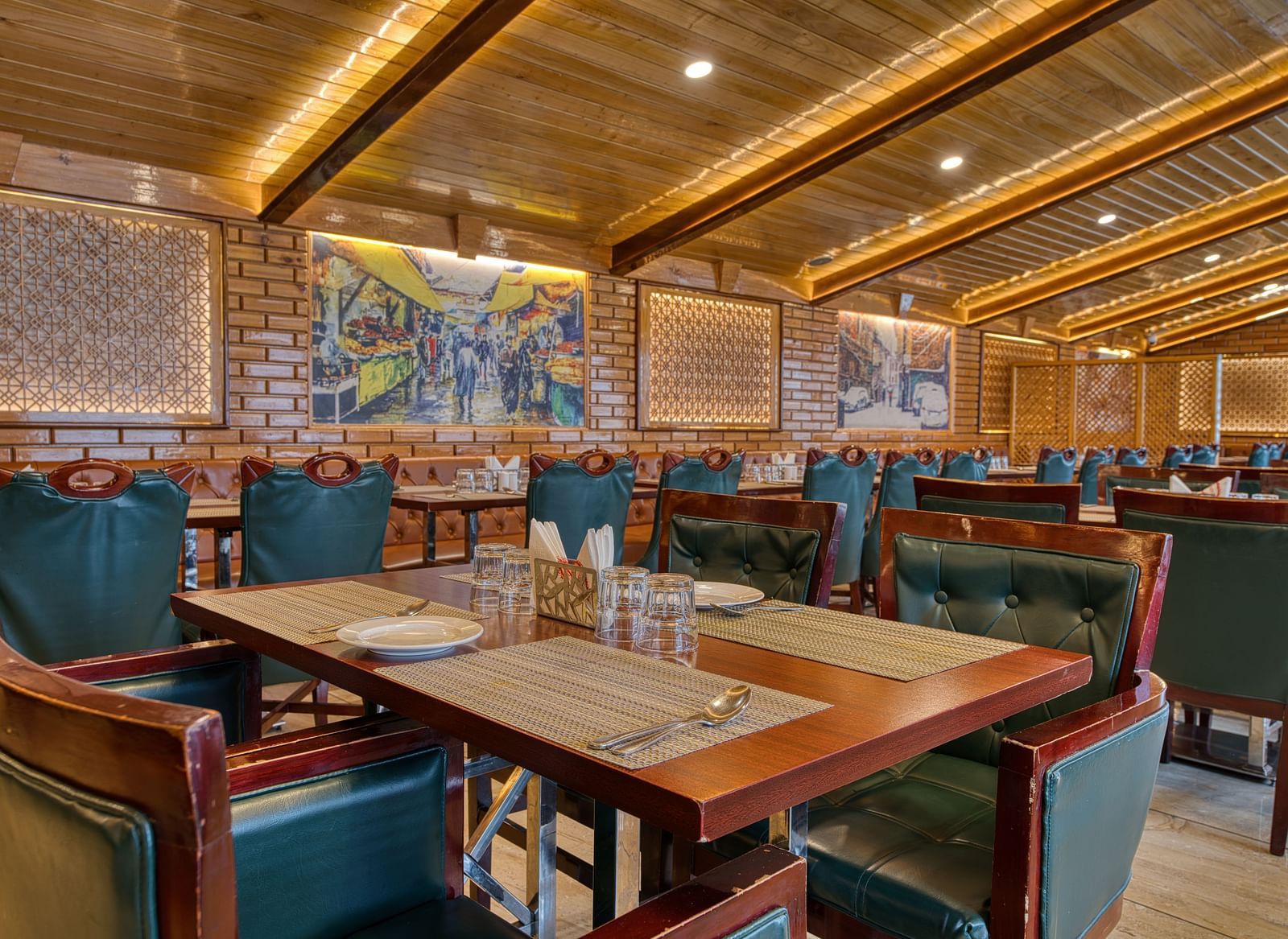 Well-lit dining area with wooden interiors and green chairs at Royal Comfort Regency, offering a warm and inviting restaurant setting.
