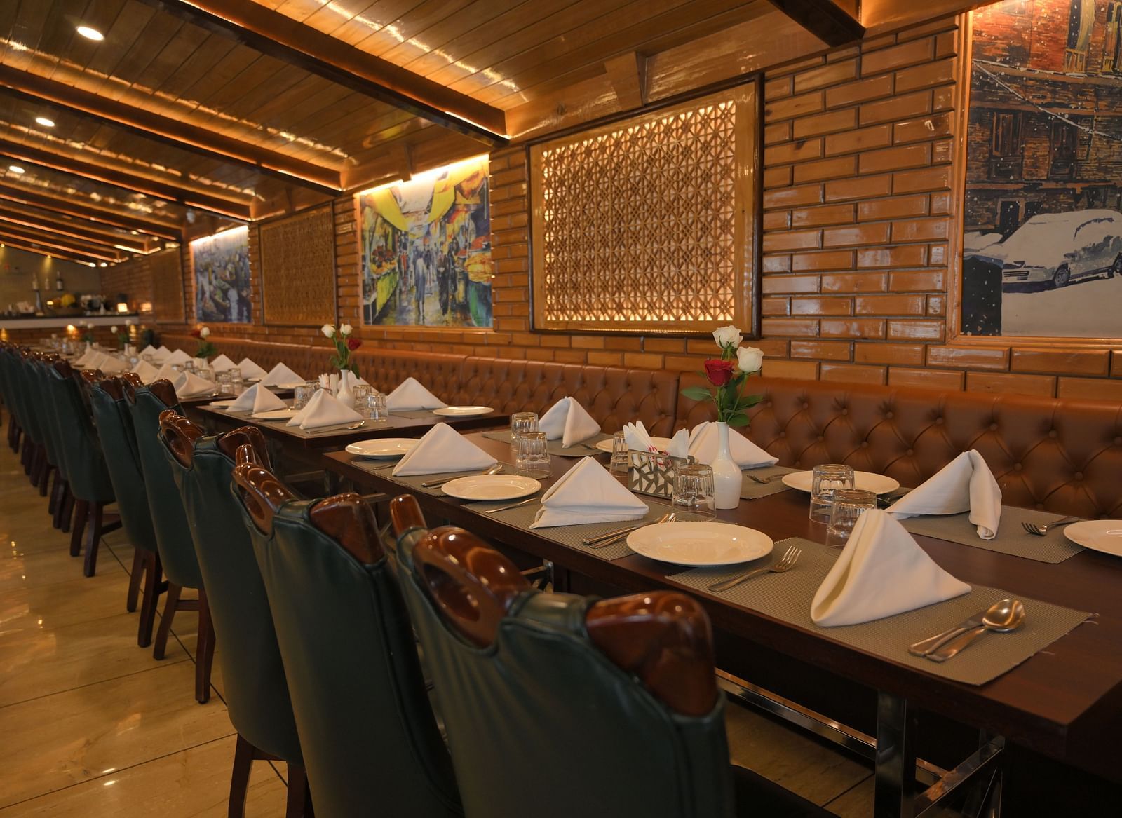 Tables and chairs arranged neatly with cutlery and decor ready for guests, with paintings on walls at Royal Comfort Regency
