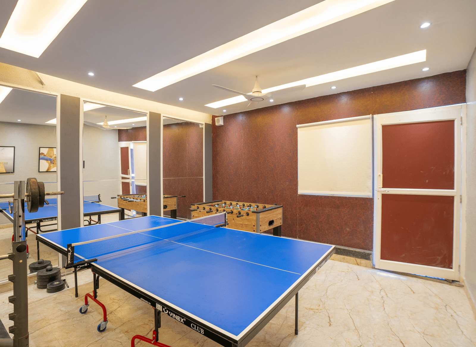 The vibrant games room at Sukoon by the Ganges features a blue table tennis table, a foosball machine, and ample space for activities.