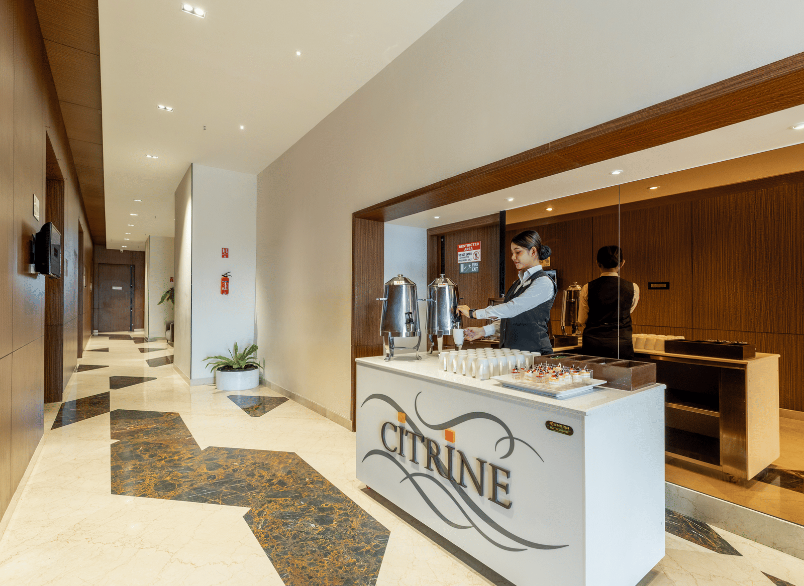The reception counter at the Citrine Hotel, with the hotel logo and a person standing behind the desk.