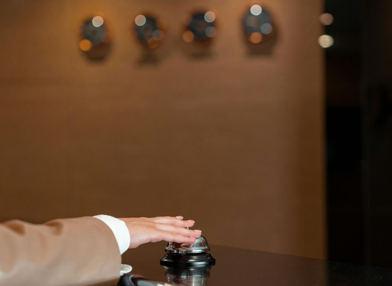 A person pressing a service bell on a counter.