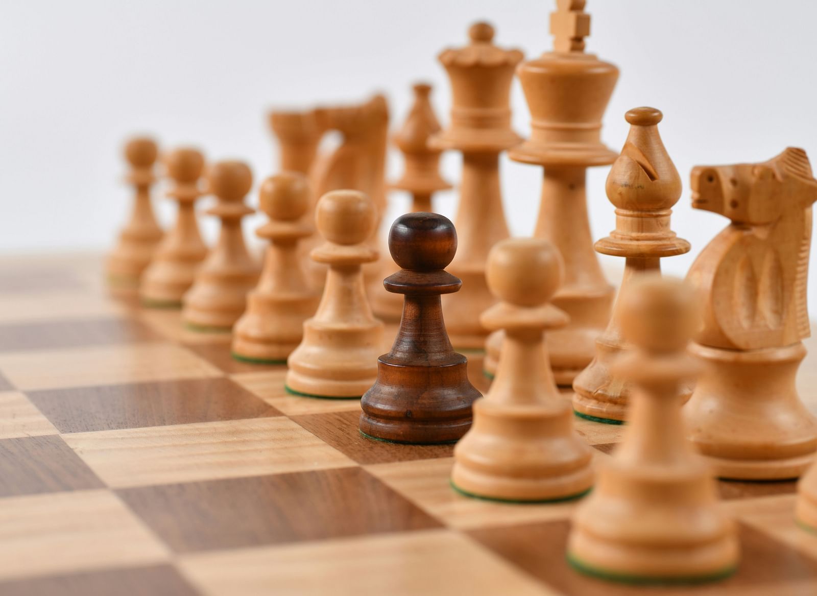 A detailed chessboard with wooden chess pieces, with a black pawn prominently in focus.