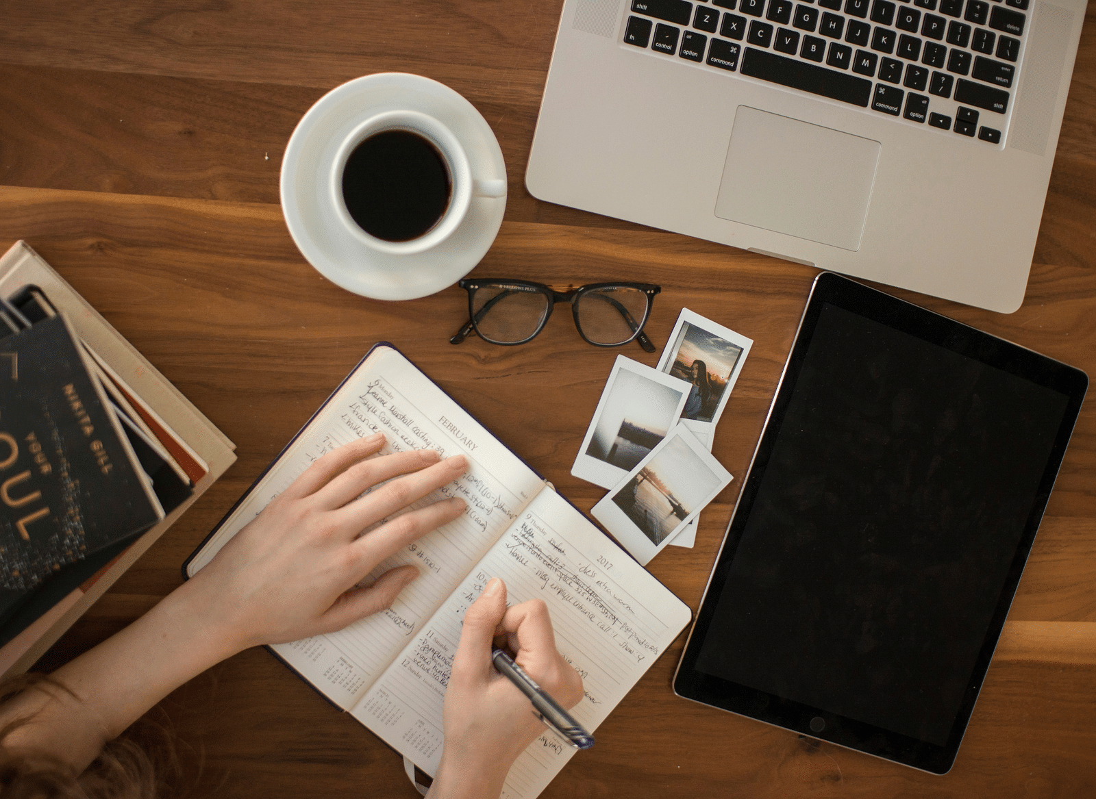 Overhead view of a desk with laptop, notebook and coffee.