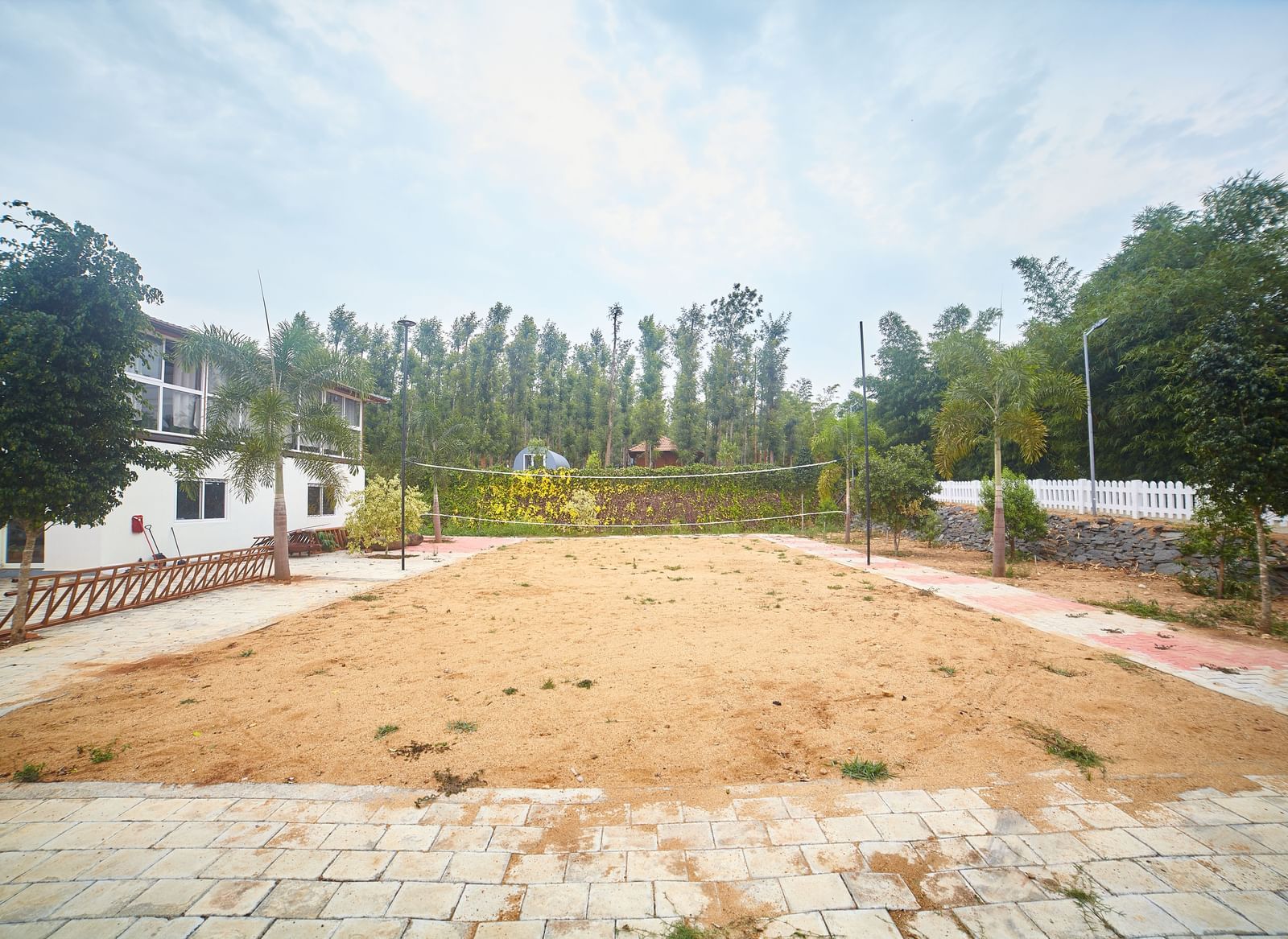 A wide, open expanse of dry, light brown ground, possibly a sports field or open space, with buildings and trees in the background under a pale sky - Vintage Trails by Ilara