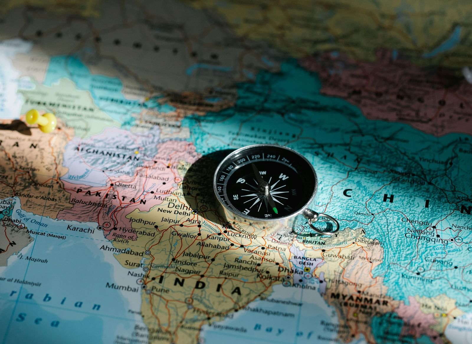 A compass placed on a world map, highlighting travel or navigation across different regions.