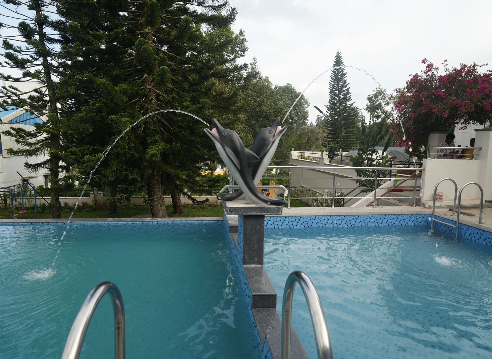 The swimming pool at WOW Naturefull Resorts with 2 dolphin statues in the middle of it.