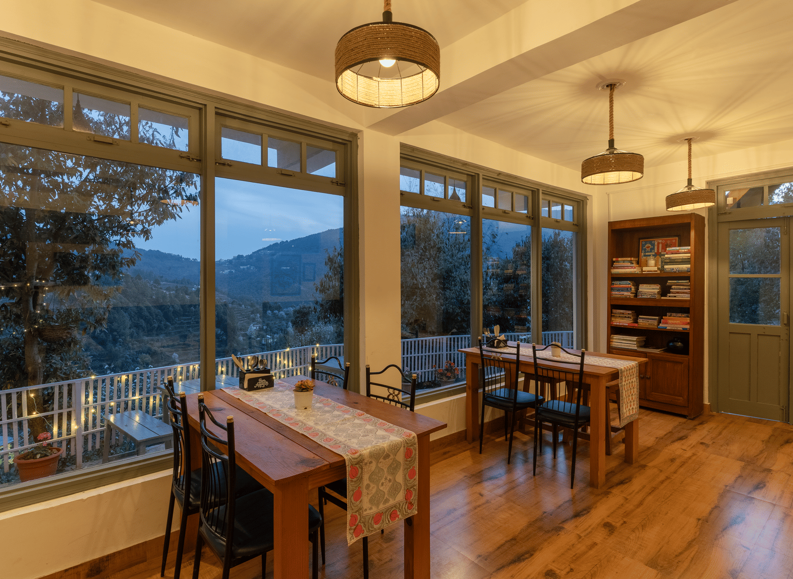 An indoor dining area with wooden tables and large windows at Ziran Retreat.