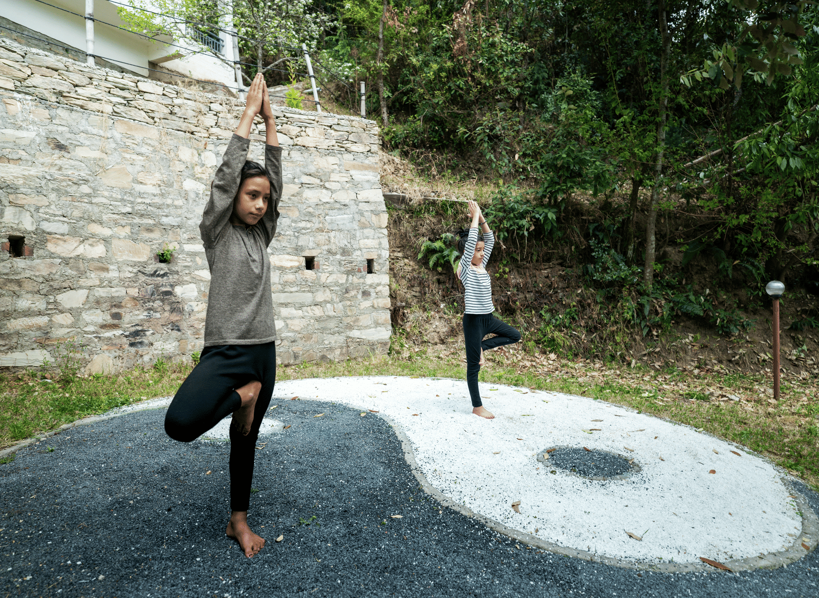 Two people are doing a tree pose on a yin-yang symbol at Ziran Retreat.