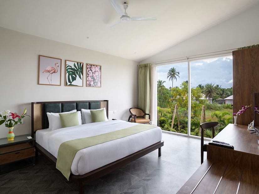 full view image of the bedroom at the Premium Suite with ample of natural light featuring a king size bed along with an elegant french window at the far end of the bedroom